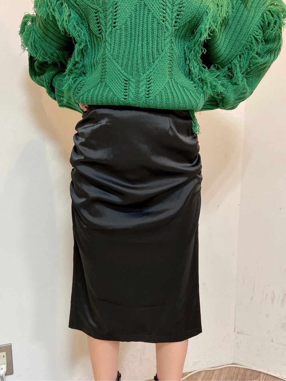 ブラック系のスカート、ブラック系のブーツ、グリーン系のニット/セーターを着用したレディースの秋コーディネートの5枚目の写真