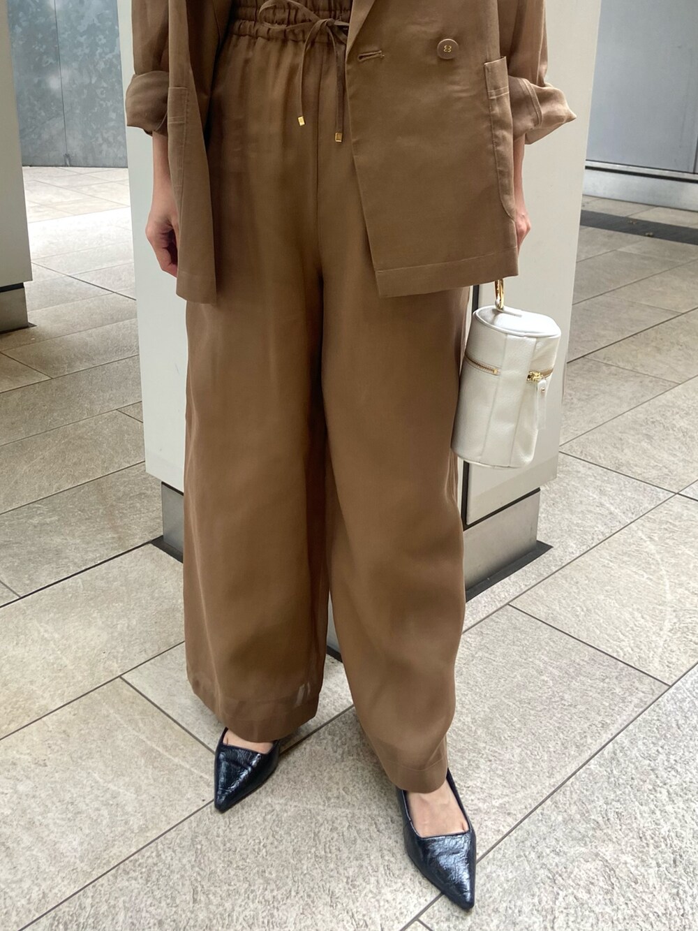 ブラウン系のその他パンツ、ブラック系のサンダル、ホワイト系のキャミソールを着用したレディースの春コーディネートの6枚目の写真