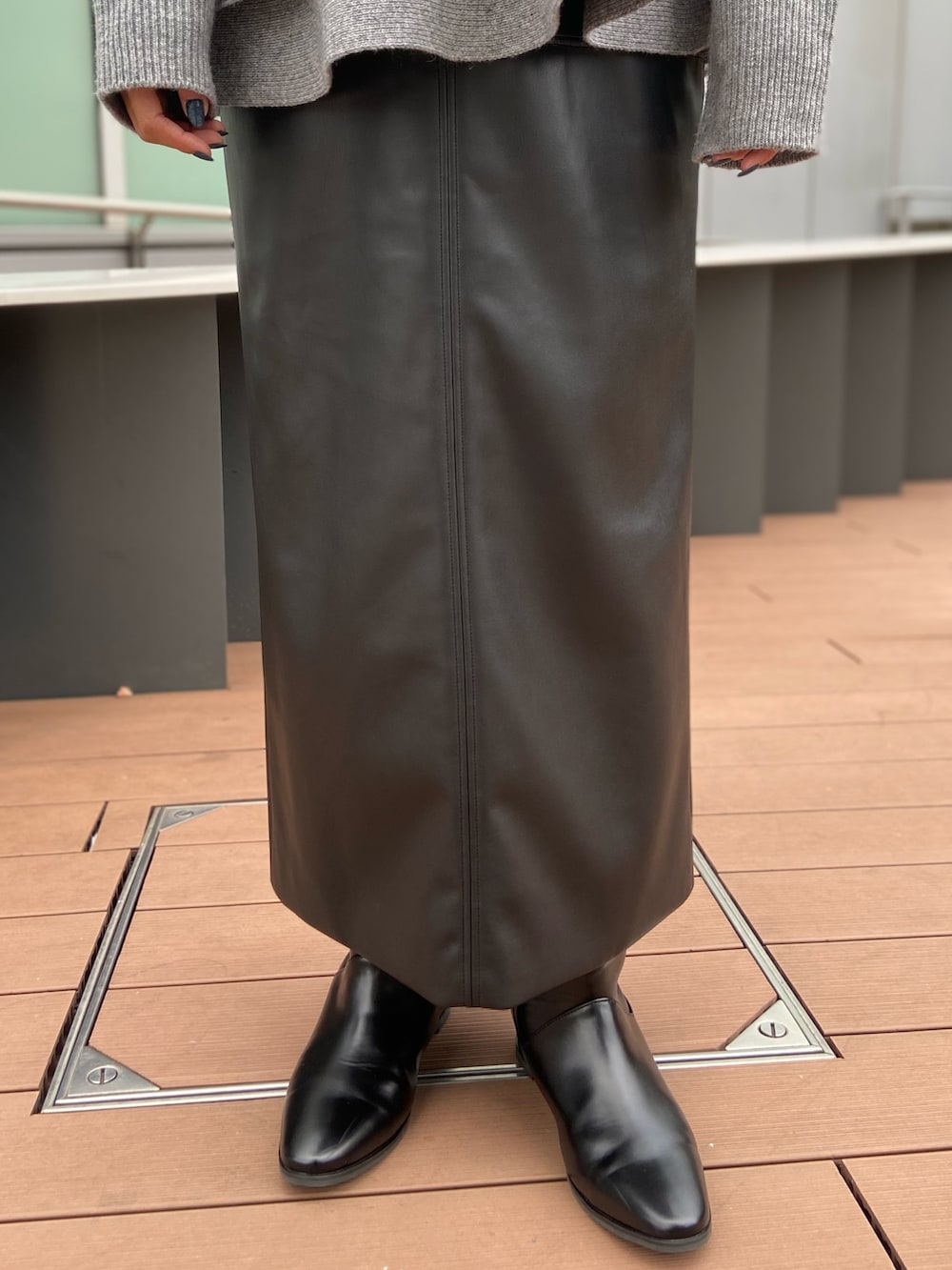 グレー系のニット/セーター、ブラック系のスカート、ブラック系のブーツを着用したレディースの秋コーディネートの6枚目の写真