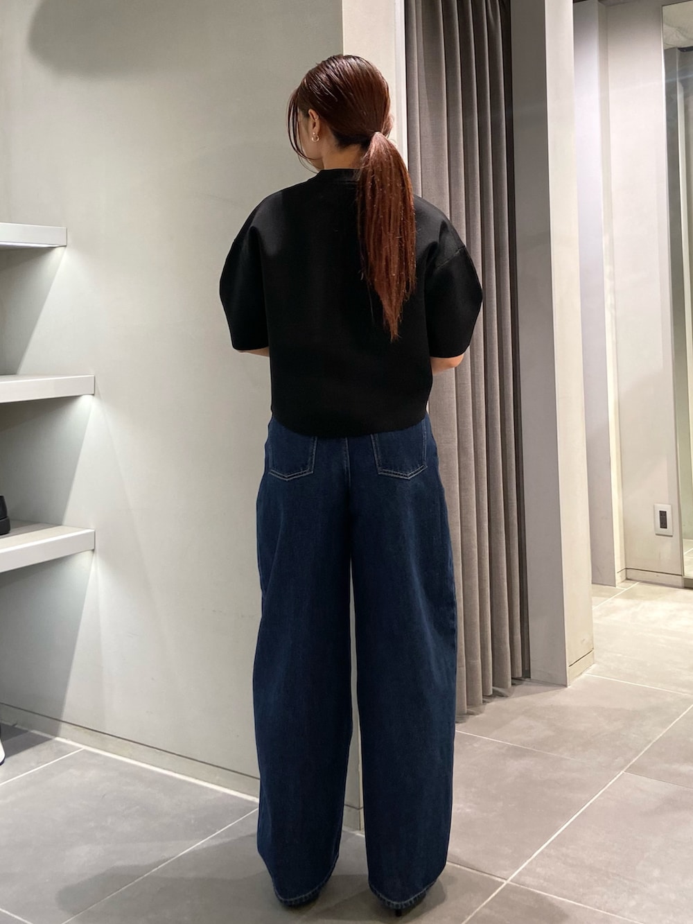 ブラック系のニット/セーター、ブルー系のデニムパンツ、ブラック系のパンプスを着用したレディースの春コーディネートの3枚目の写真