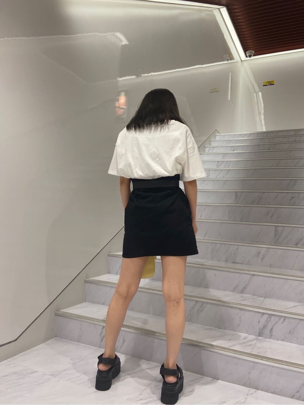 ブラック系のサンダル、ホワイト系のTシャツ/カットソー、ブラック系のスカートを着用したレディースの夏コーディネートの4枚目の写真