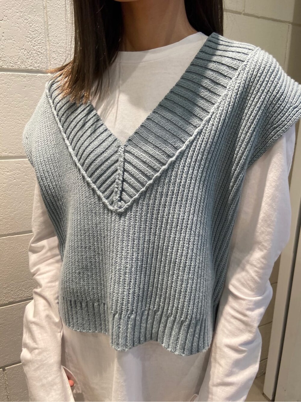 ブラック系のスカート、ブラック系のブーツ、ブルー系のベストを着用したレディースの春コーディネートの4枚目の写真