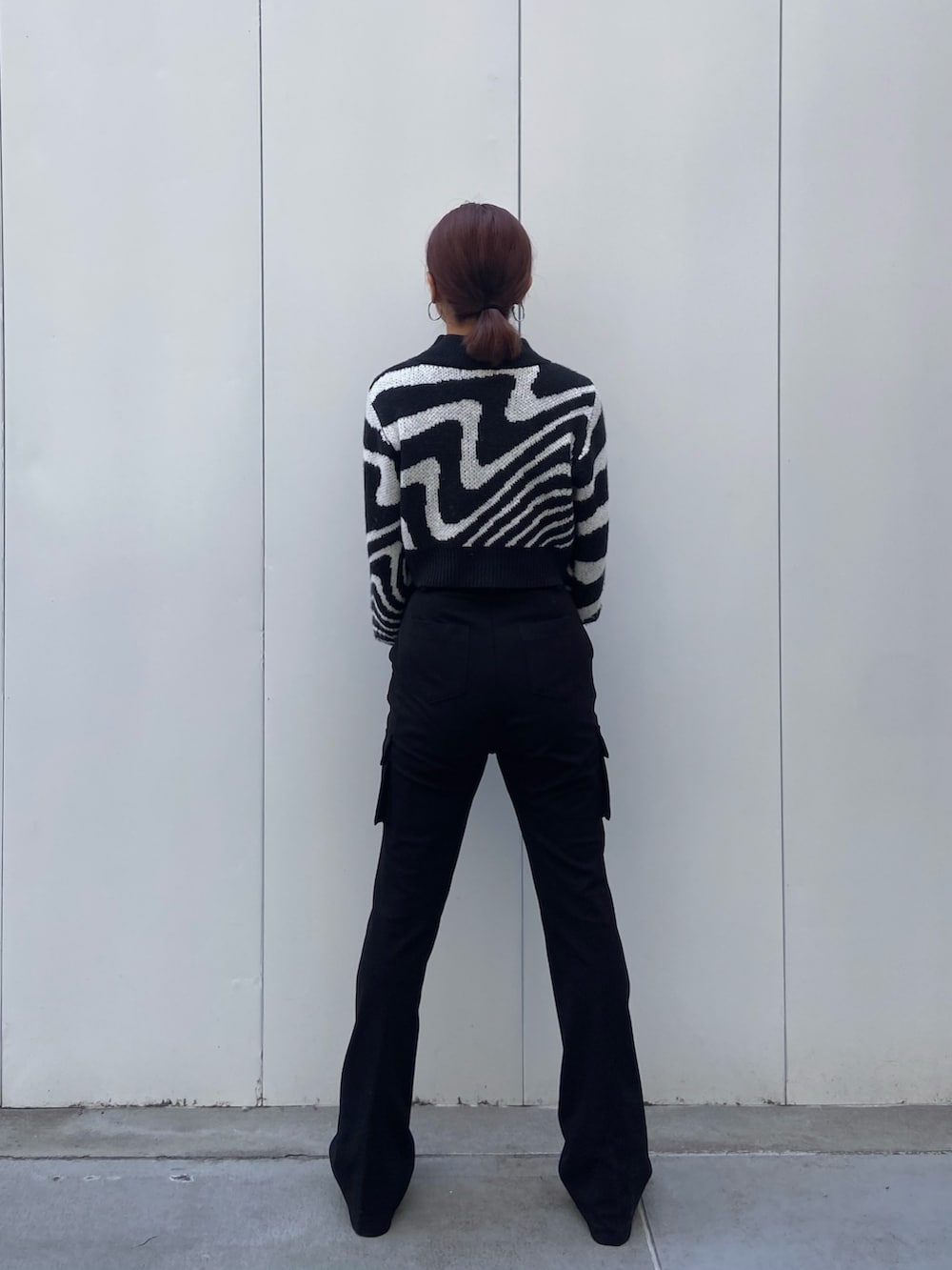 ブラック系のニット/セーター、ブラック系のカーゴパンツ、ブラック系のブーツを着用したレディースの冬コーディネートの3枚目の写真