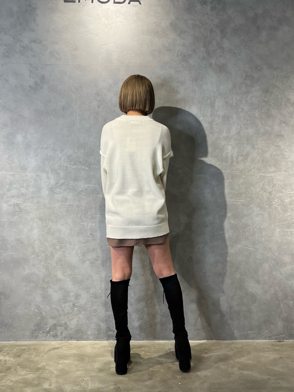 ホワイト系のニット/セーター、ベージュ系のスカート、ブラック系のブーツを着用したレディースの冬コーディネートの3枚目の写真