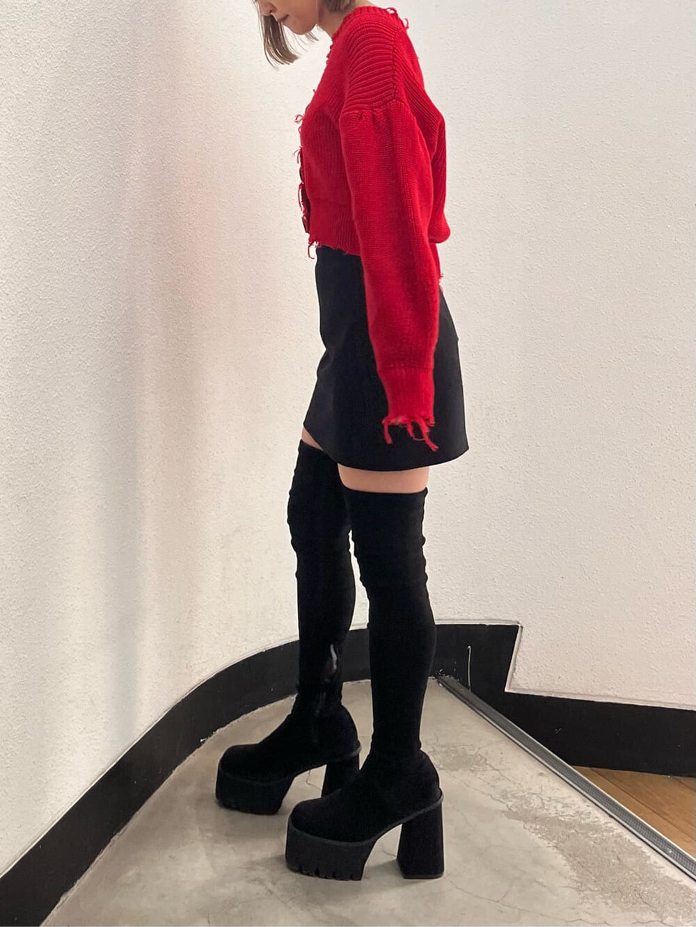 ブラック系のスカート、レッド系のカーディガン/ボレロ、ブラック系のブーツを着用したレディースの秋コーディネートの2枚目の写真