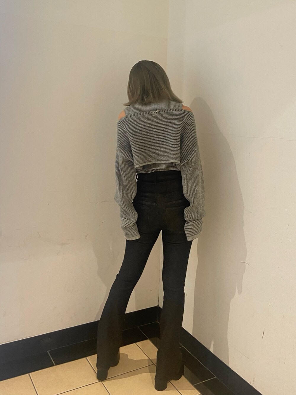 グレー系のニット/セーター、ブラック系のデニムパンツ、ブラック系のブーツを着用したレディースの秋コーディネートの3枚目の写真