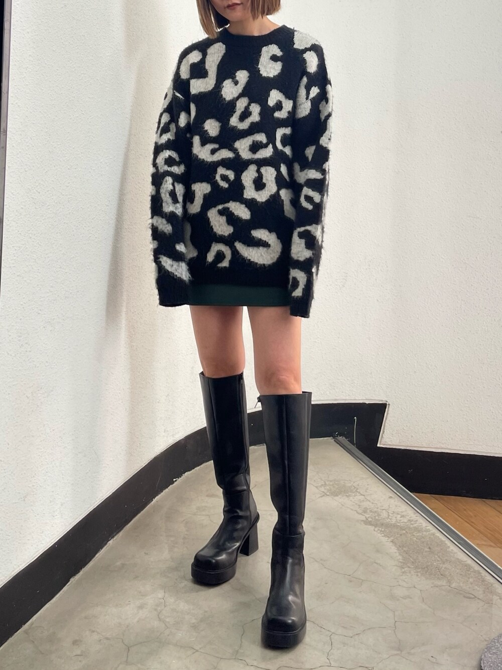 ブラック系のニット/セーター、グリーン系のスカート、ブラック系のブーツを着用したレディースの冬コーディネートの2枚目の写真