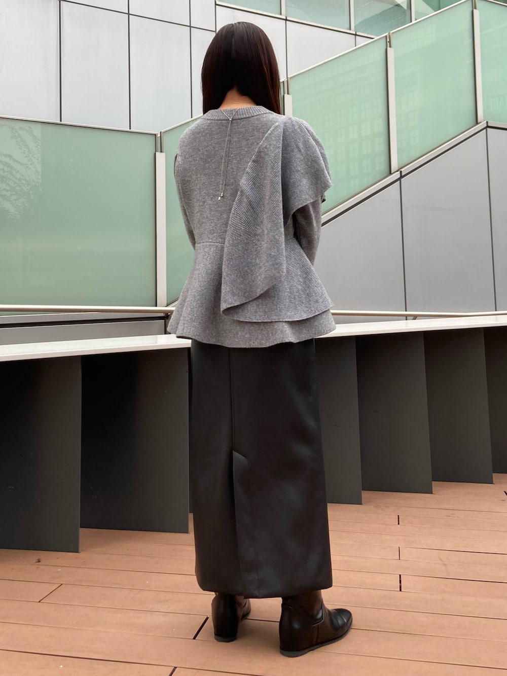 グレー系のニット/セーター、ブラック系のスカート、ブラック系のブーツを着用したレディースの秋コーディネートの3枚目の写真