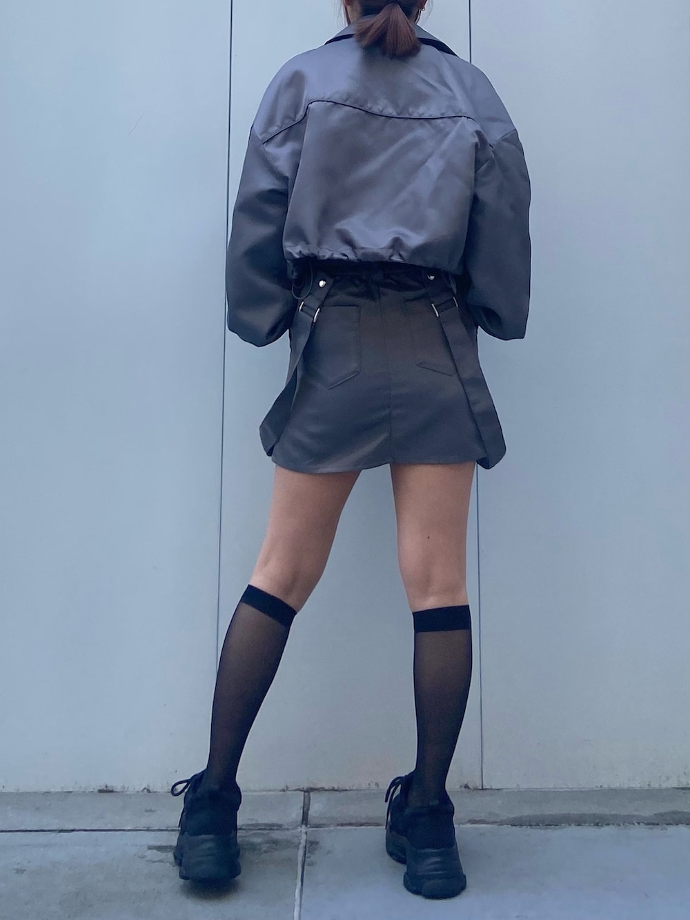 グレー系のブルゾン、ブラック系のキャミソール、グレー系のスカートを着用したレディースの冬コーディネートの3枚目の写真