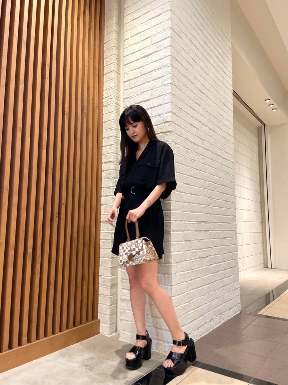 その他のハンドバッグ、ブラック系のワンピース、ブラック系のサンダルを着用したレディースの春コーディネートの2枚目の写真