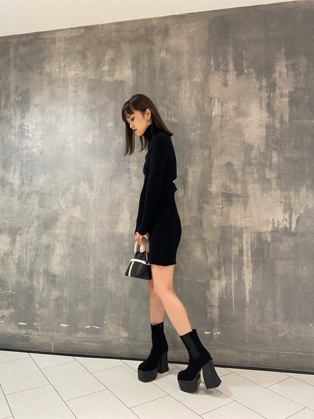 ブラック系のブーツ、ブラック系のワンピース、ブラック系のショルダーバッグを着用したレディースの冬コーディネートの6枚目の写真