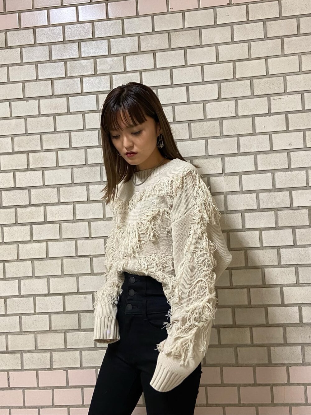 ブラック系のデニムパンツ、ホワイト系のハンドバッグ、ブラック系のブーツを着用したレディースの冬コーディネートの2枚目の写真