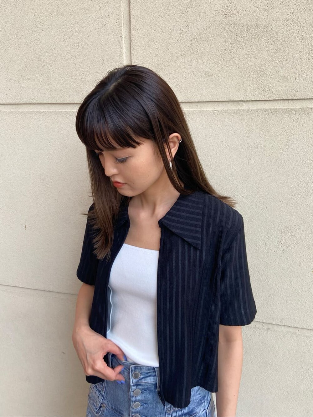 ブルー系のデニムパンツ、ホワイト系のタンクトップ、ブラック系のサンダルを着用したレディースの春コーディネートの4枚目の写真