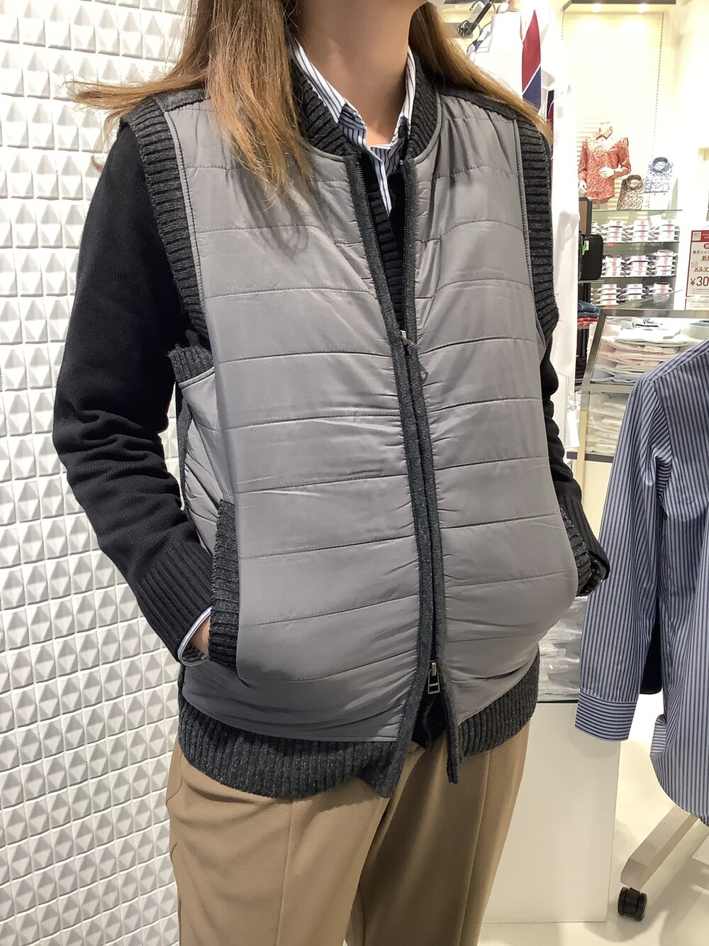 グレー系のニット/セーター、ブラック系のカーディガン/ボレロ、ブルー系のビジネスシャツを着用したレディースの秋コーディネートの2枚目の写真