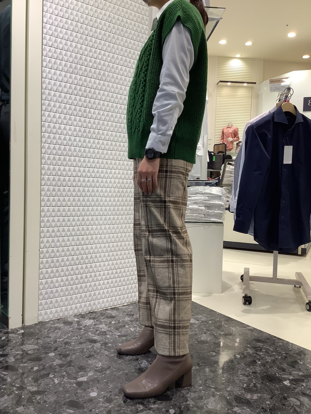 グリーン系のベスト、ホワイト系のビジネスシャツを着用したレディースの冬コーディネートの2枚目の写真