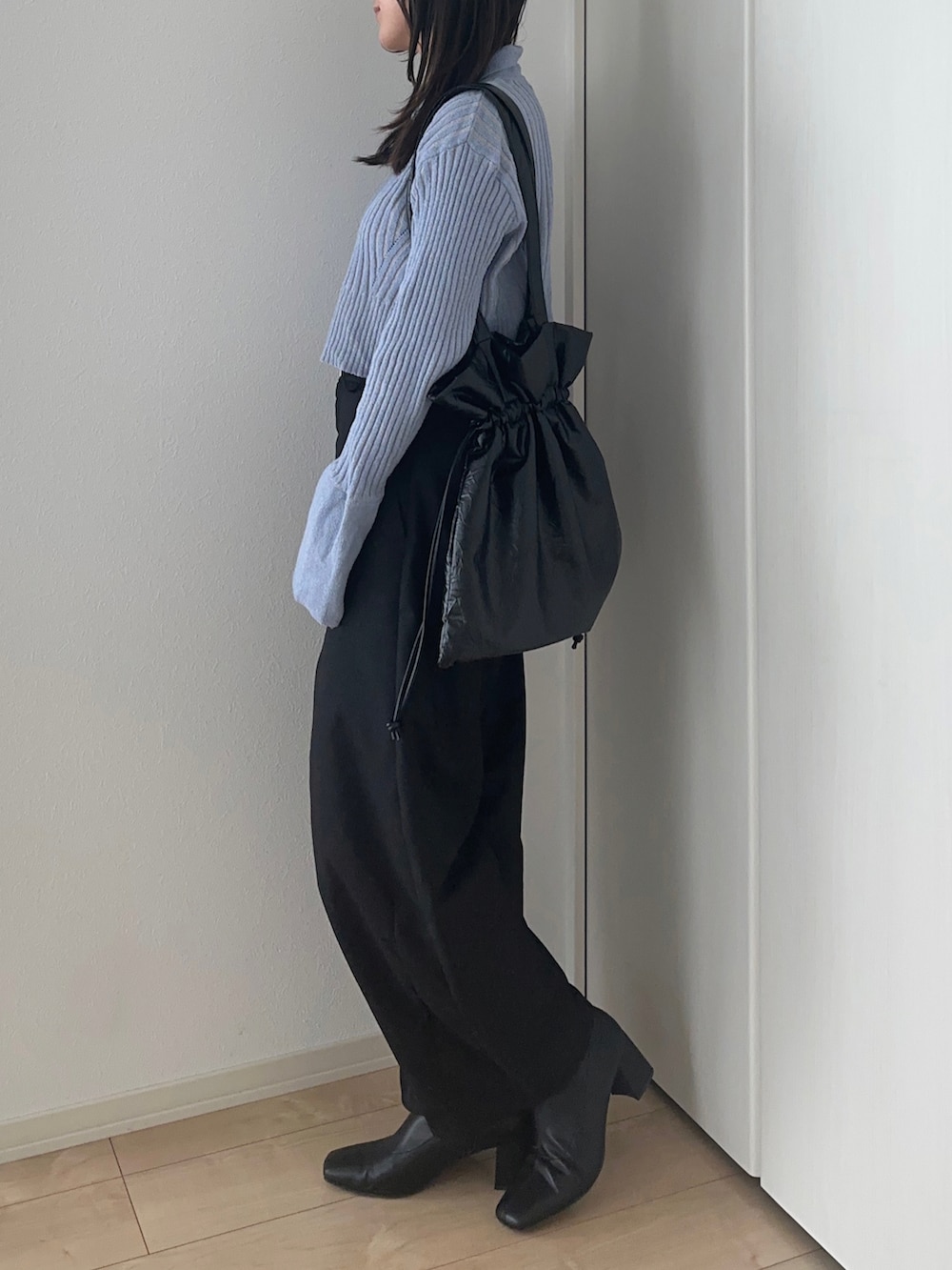 ブルー系のニット/セーター、ブラック系のスラックス、ブラック系のトートバッグを着用したレディースの冬コーディネートの2枚目の写真