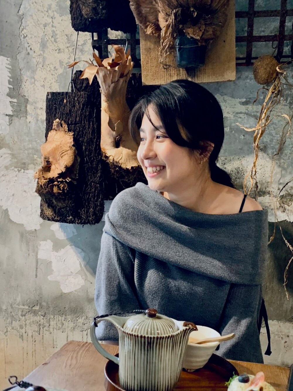 グレー系のニット/セーター、ゴールド系のピアス（両耳用）を着用したレディースの春コーディネートの2枚目の写真