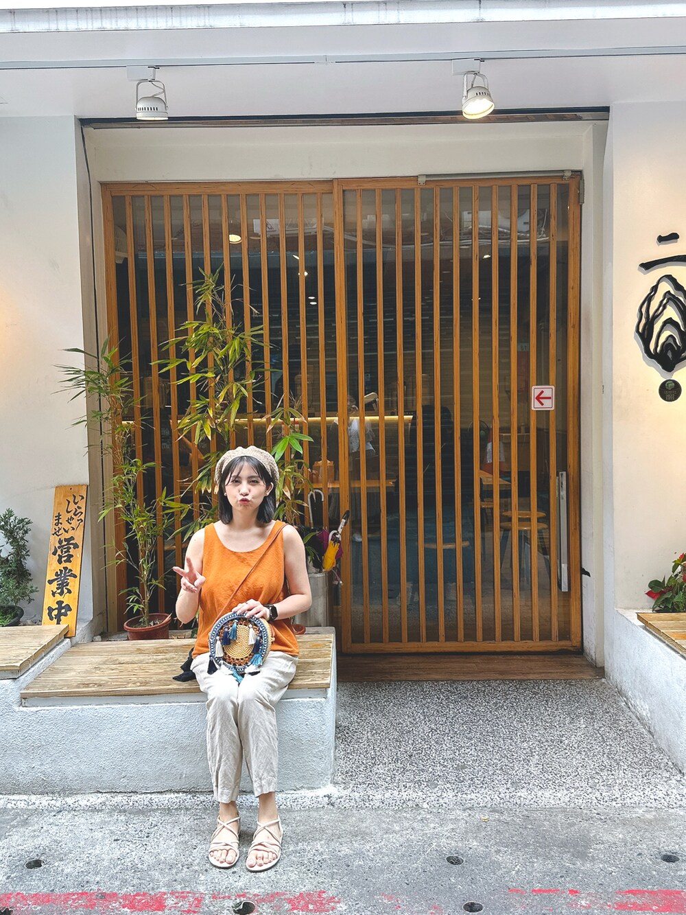 ベージュ系のチノパンツ、オレンジ系のキャミソール、ホワイト系のサンダルを着用したレディースの春コーディネートの2枚目の写真