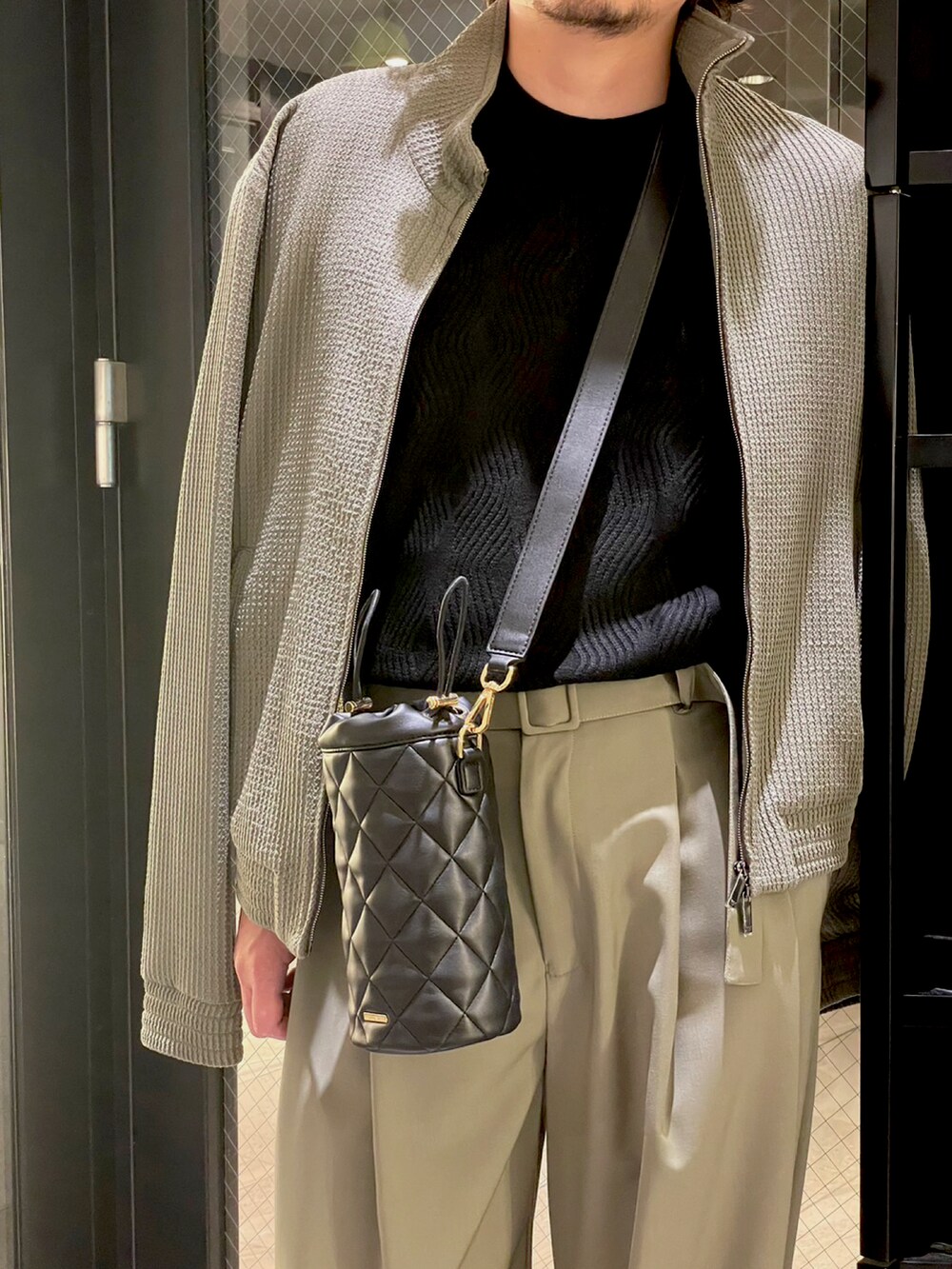 ブラック系のサンダル、グリーン系のスラックス、ブラック系のボディバッグ/ウエストポーチを着用したメンズの夏コーディネートの2枚目の写真