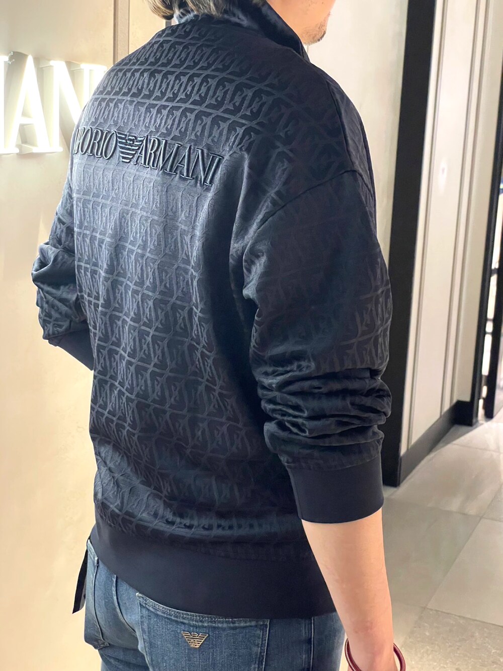 ブルー系のデニムパンツ、ブラック系のスウェット、ホワイト系のTシャツ/カットソーを着用したメンズの春コーディネートの4枚目の写真