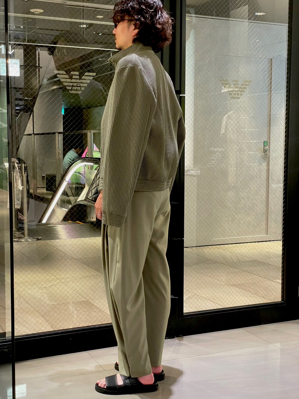 ブラック系のサンダル、グリーン系のスラックス、ブラック系のボディバッグ/ウエストポーチを着用したメンズの夏コーディネートの5枚目の写真