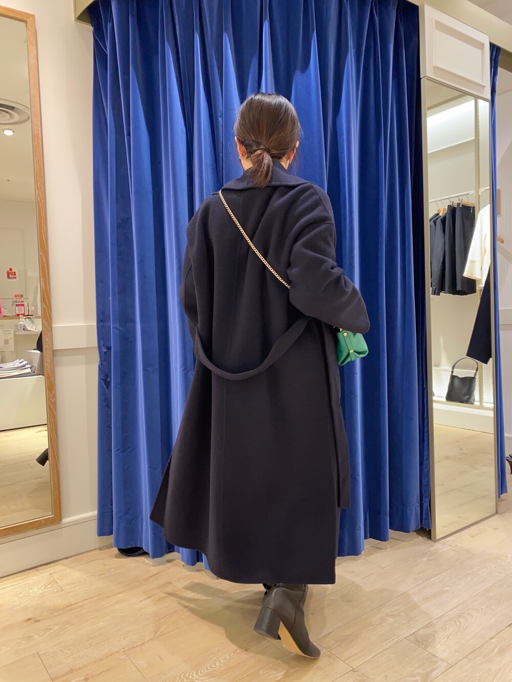 ベージュ系のカーディガン/ボレロ、ホワイト系のシャツ/ブラウス、ブラック系のブーツを着用したレディースの冬コーディネートの2枚目の写真