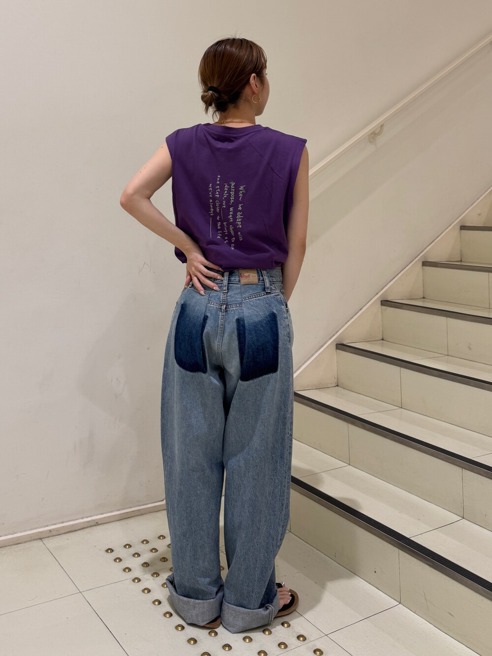 パープル系のタンクトップ、ブルー系のデニムパンツを着用したレディースの夏コーディネートの3枚目の写真