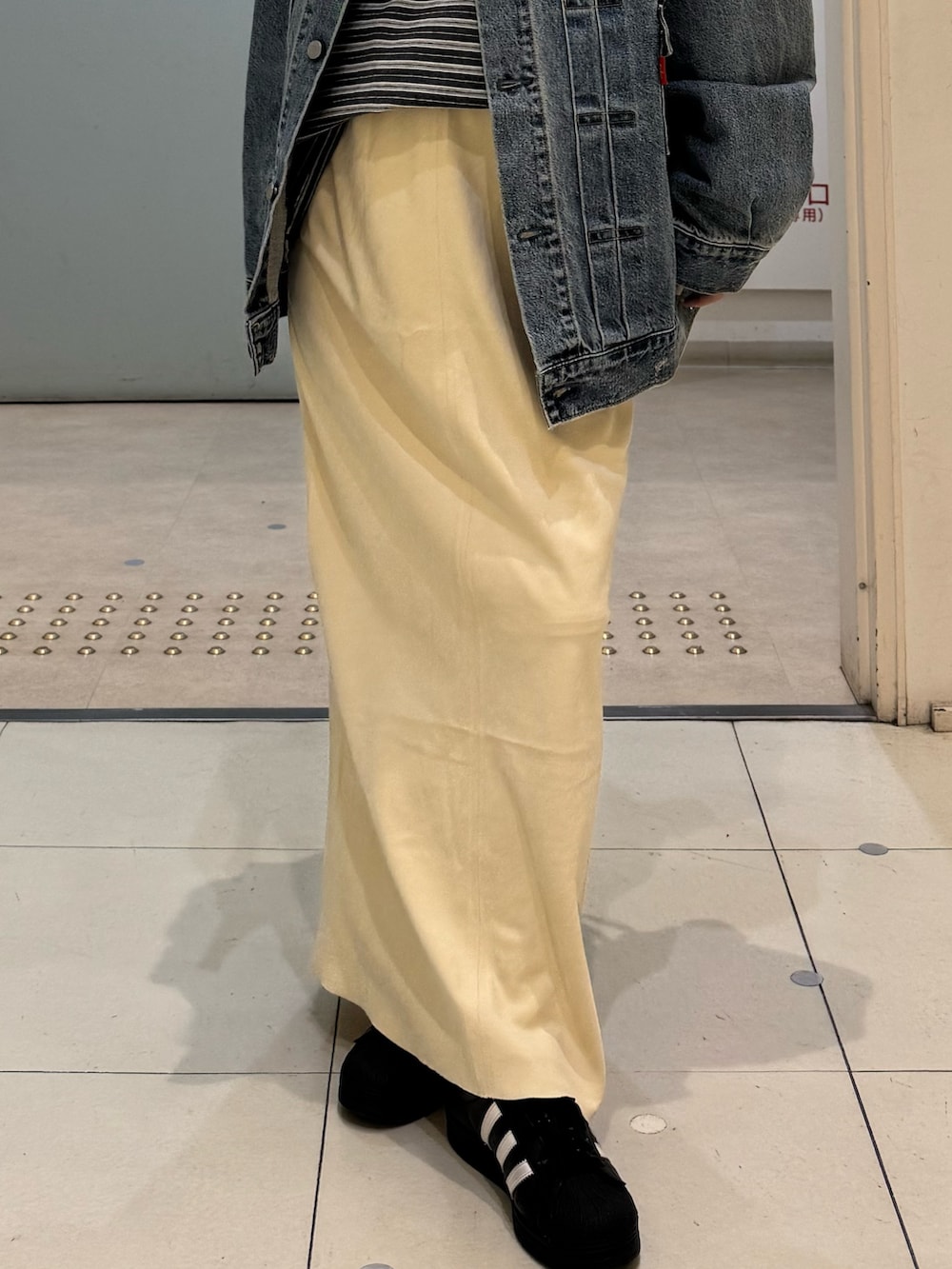 グレー系のTシャツ/カットソー、ブルー系のデニムジャケット、イエロー系のスカートを着用したレディースの冬コーディネートの5枚目の写真