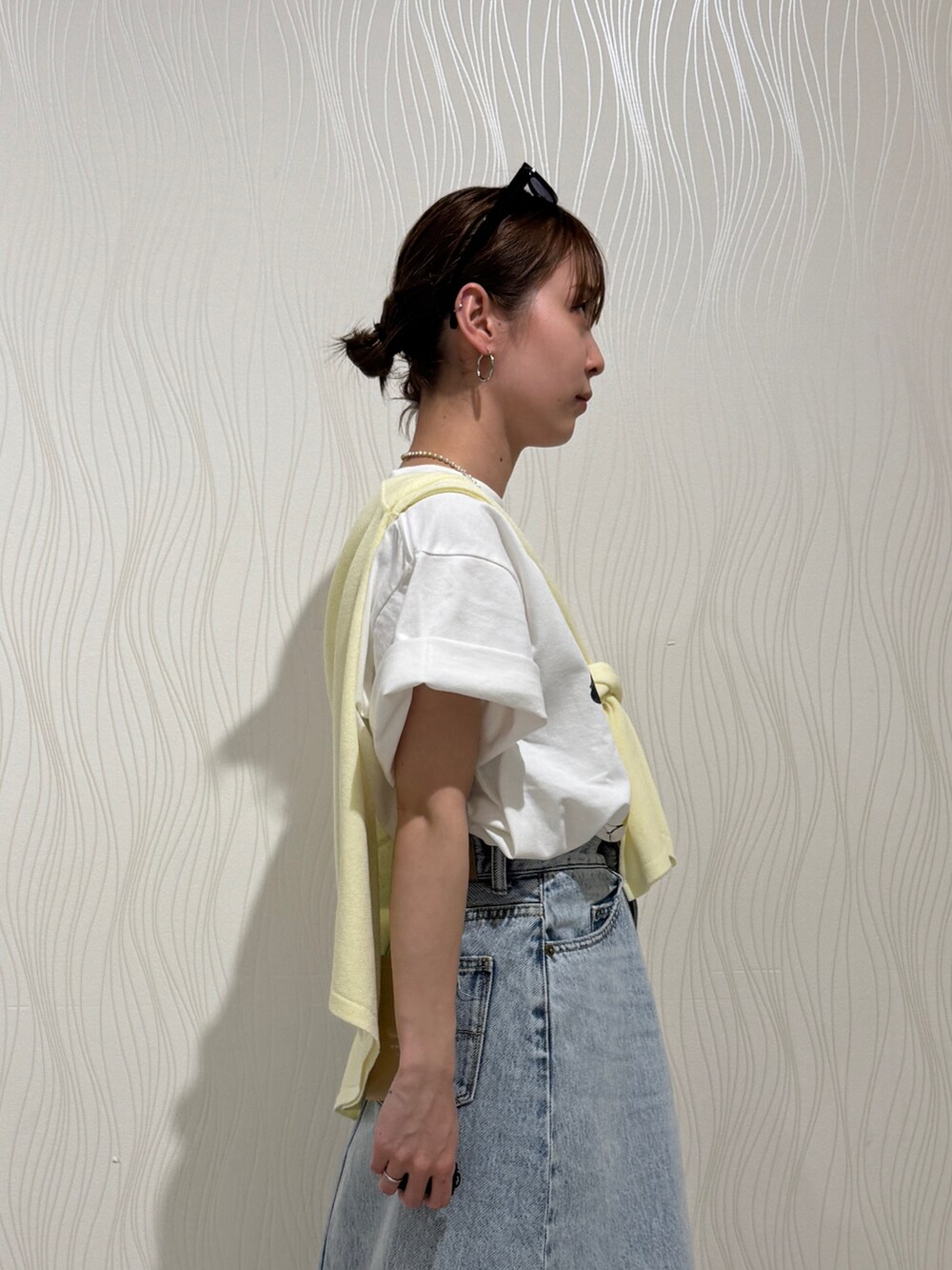 ホワイト系のTシャツ/カットソー、イエロー系のニット/セーター、ブルー系のスカートを着用したレディースの春コーディネートの5枚目の写真