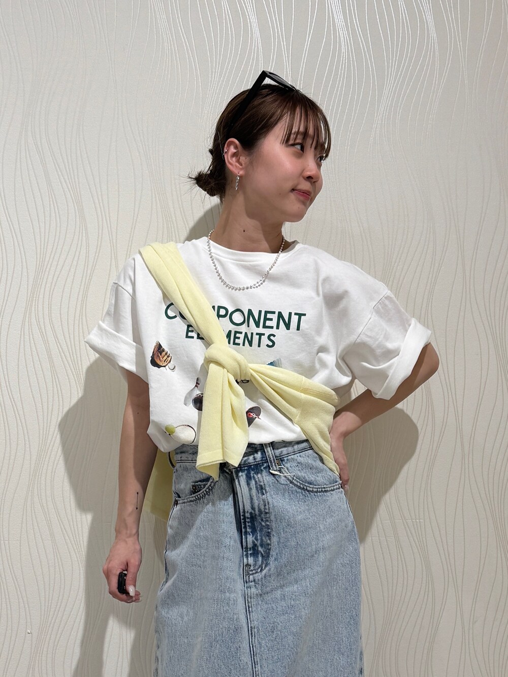 ホワイト系のTシャツ/カットソー、イエロー系のニット/セーター、ブルー系のスカートを着用したレディースの春コーディネートの4枚目の写真