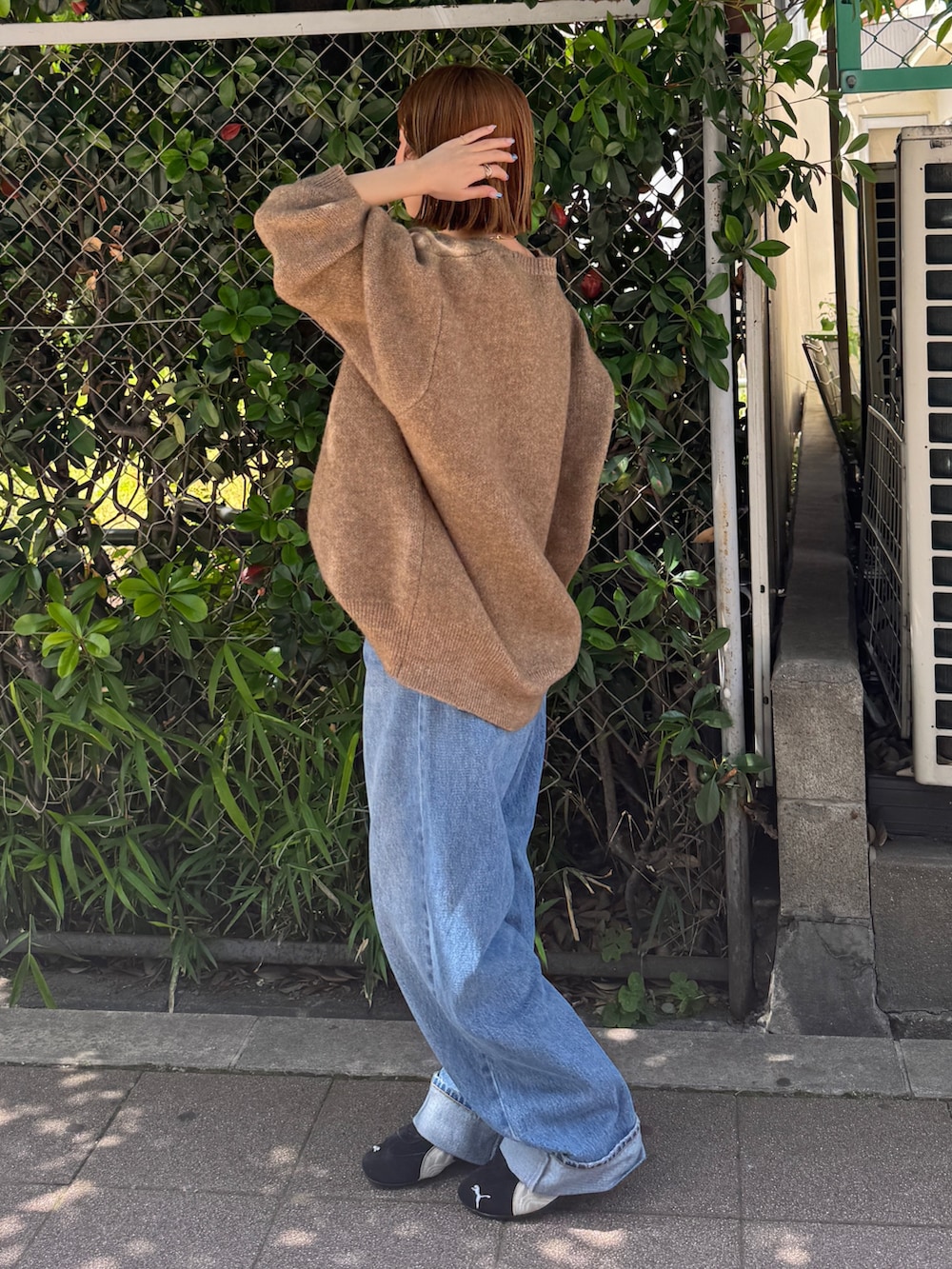 ブラック系のスニーカー、ベージュ系のニット/セーター、ブルー系のデニムパンツを着用したレディースの夏コーディネートの2枚目の写真