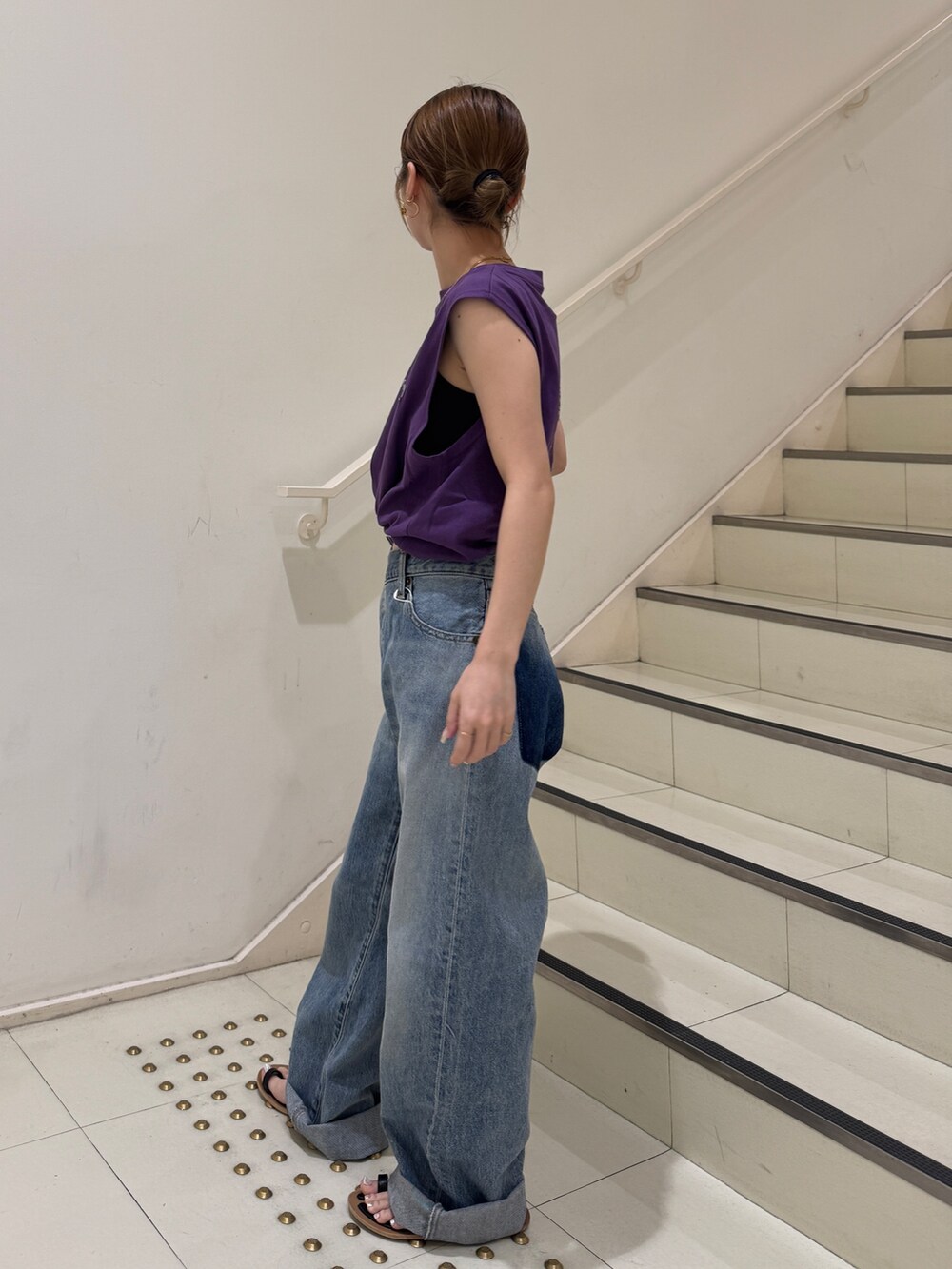 パープル系のタンクトップ、ブルー系のデニムパンツを着用したレディースの夏コーディネートの2枚目の写真