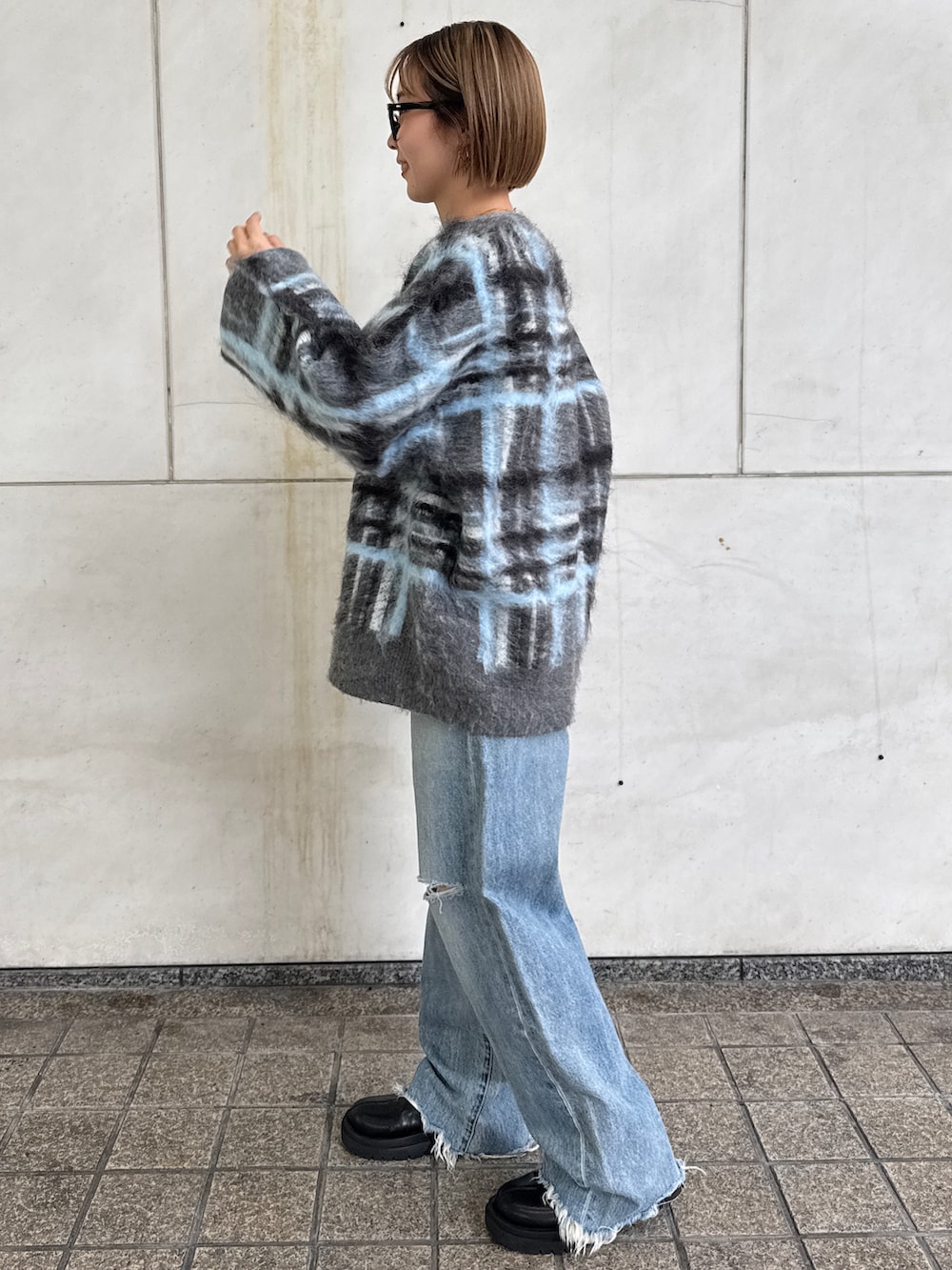 グレー系のニット/セーター、ホワイト系のTシャツ/カットソー、ブルー系のデニムパンツを着用したレディースの秋コーディネートの3枚目の写真