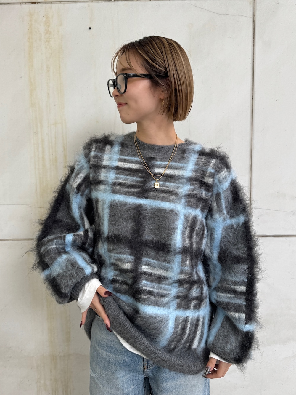 グレー系のニット/セーター、ホワイト系のTシャツ/カットソー、ブルー系のデニムパンツを着用したレディースの秋コーディネートの5枚目の写真