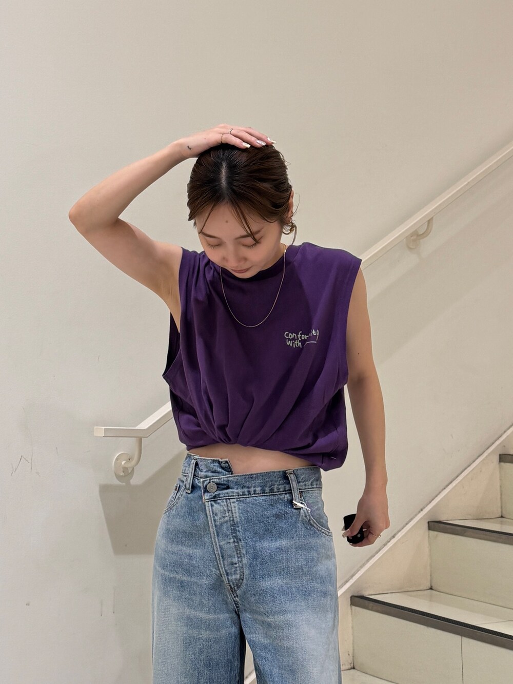 パープル系のタンクトップ、ブルー系のデニムパンツを着用したレディースの夏コーディネートの4枚目の写真