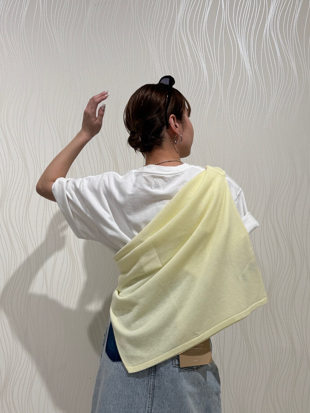 ホワイト系のTシャツ/カットソー、イエロー系のニット/セーター、ブルー系のスカートを着用したレディースの春コーディネートの6枚目の写真