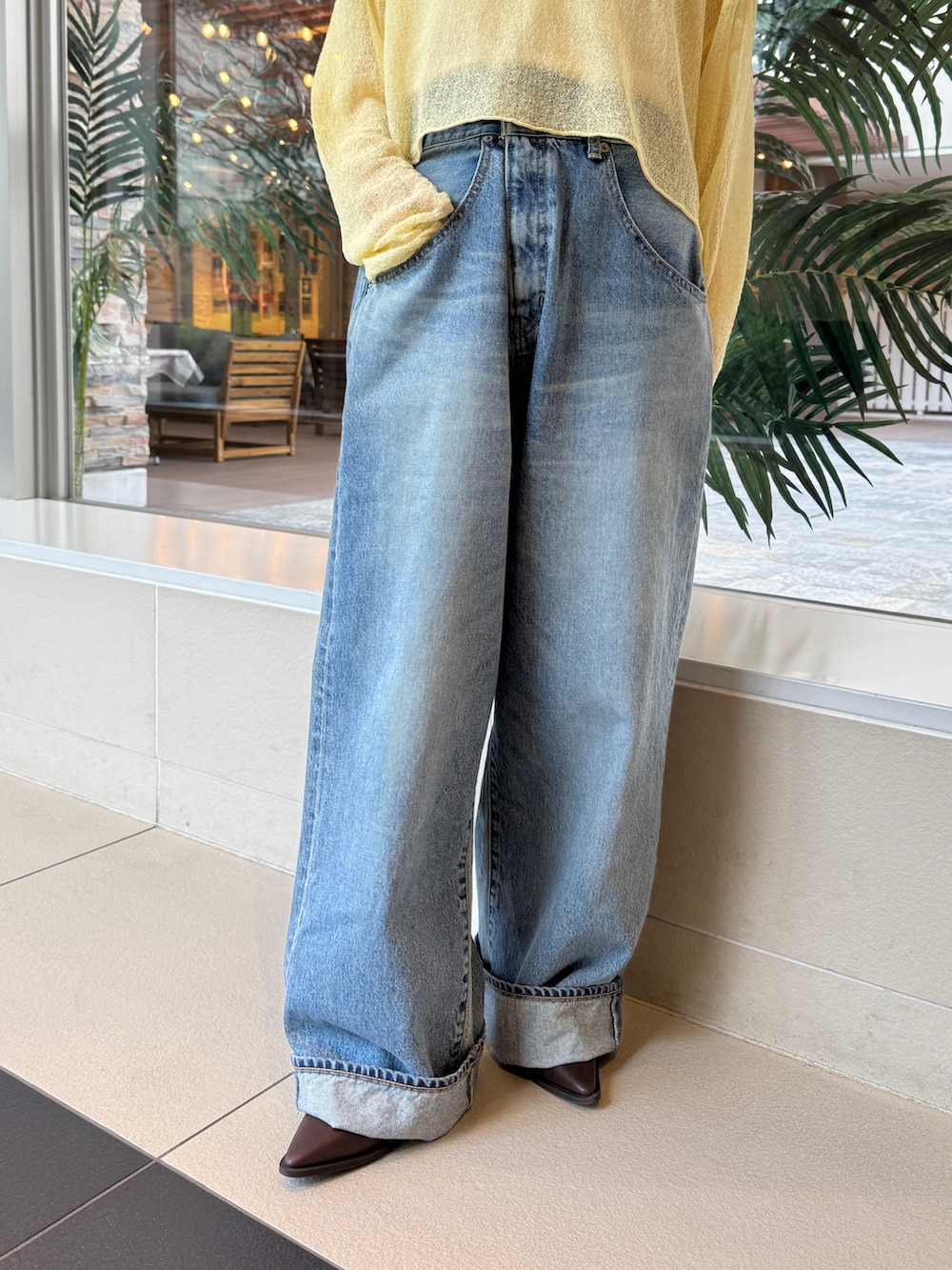 イエロー系のニット/セーター、ブルー系のデニムパンツを着用したレディースの冬コーディネートの5枚目の写真