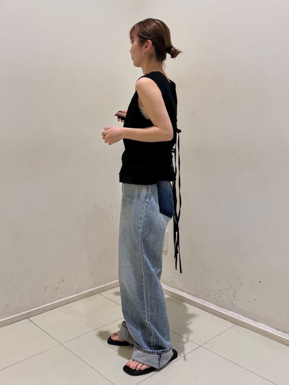 ブラック系のタンクトップ、ブルー系のデニムパンツ、ブラック系のサンダルを着用したレディースの春コーディネートの2枚目の写真