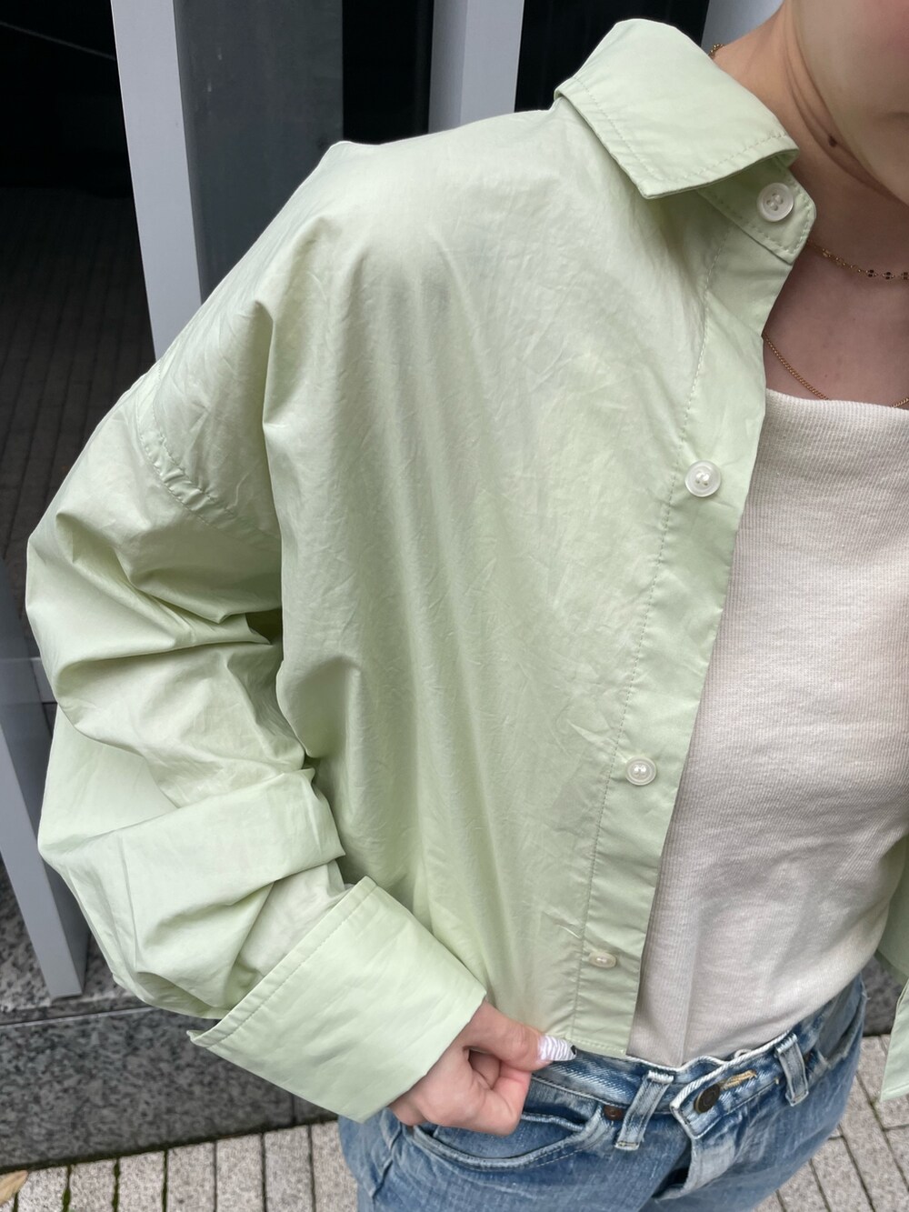 グリーン系のシャツ/ブラウス、ホワイト系のキャミソール、ブルー系のデニムパンツを着用したレディースの春コーディネートの7枚目の写真