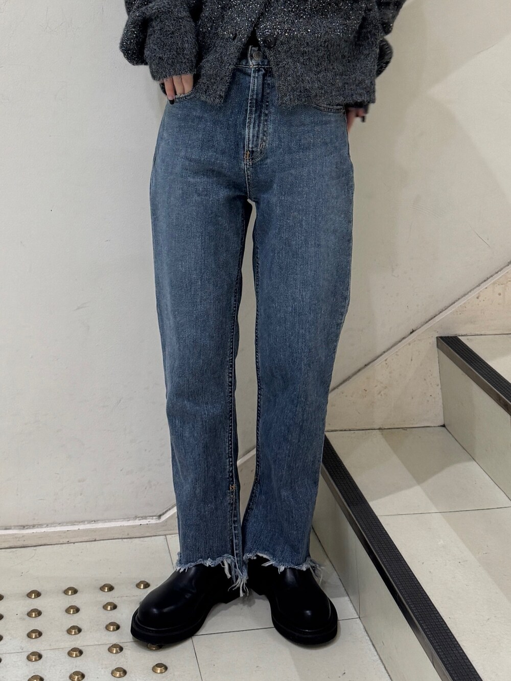 グレー系のカーディガン/ボレロ、ブラック系のニット/セーター、ブルー系のデニムパンツを着用したレディースの冬コーディネートの5枚目の写真