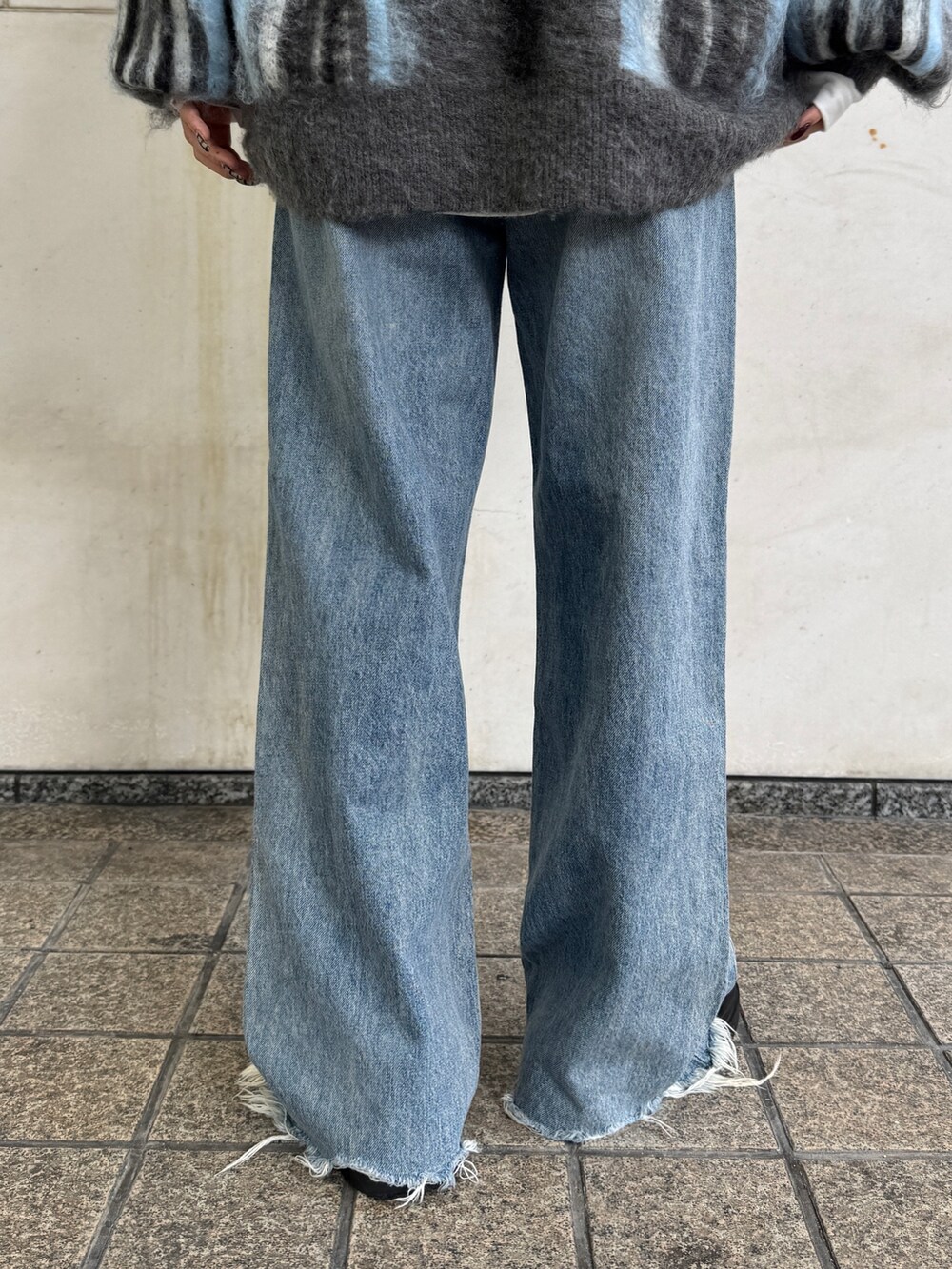 グレー系のニット/セーター、ホワイト系のTシャツ/カットソー、ブルー系のデニムパンツを着用したレディースの秋コーディネートの9枚目の写真