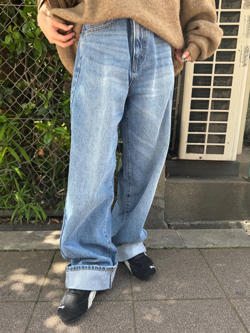 ブラック系のスニーカー、ベージュ系のニット/セーター、ブルー系のデニムパンツを着用したレディースの夏コーディネートの8枚目の写真