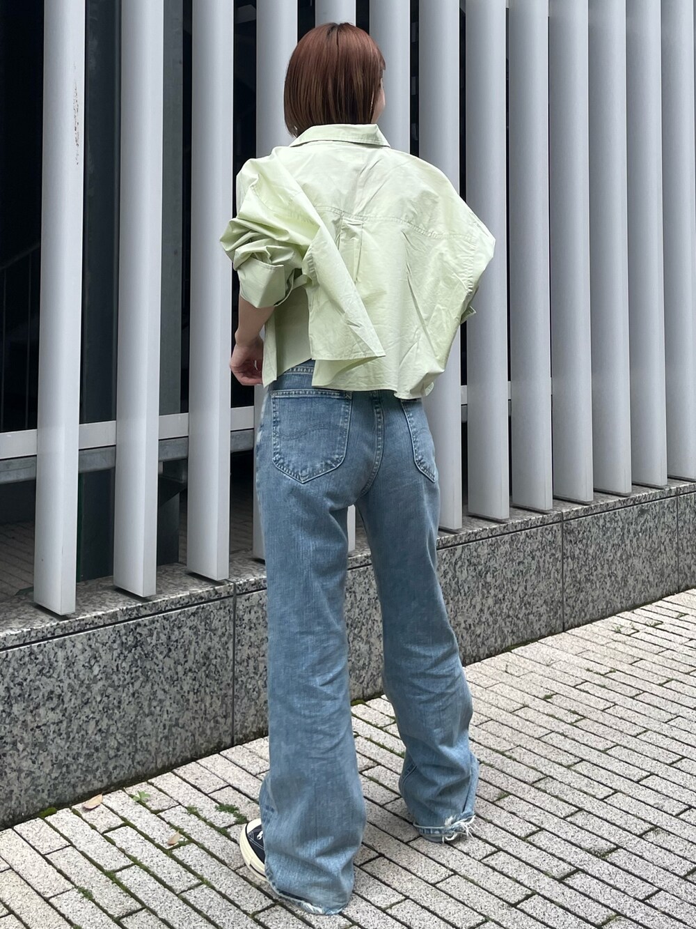 グリーン系のシャツ/ブラウス、ホワイト系のキャミソール、ブルー系のデニムパンツを着用したレディースの春コーディネートの2枚目の写真