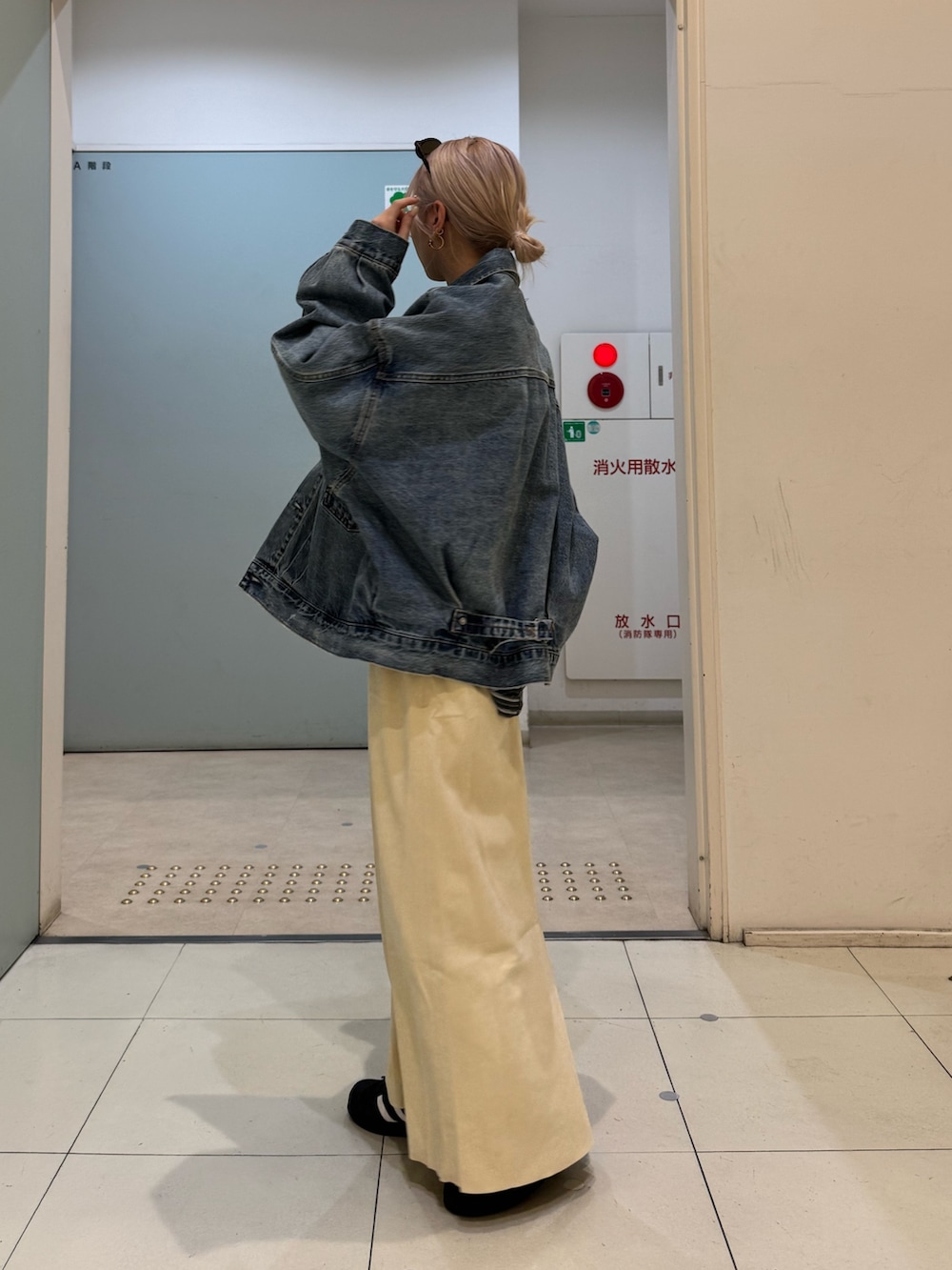 グレー系のTシャツ/カットソー、ブルー系のデニムジャケット、イエロー系のスカートを着用したレディースの冬コーディネートの2枚目の写真