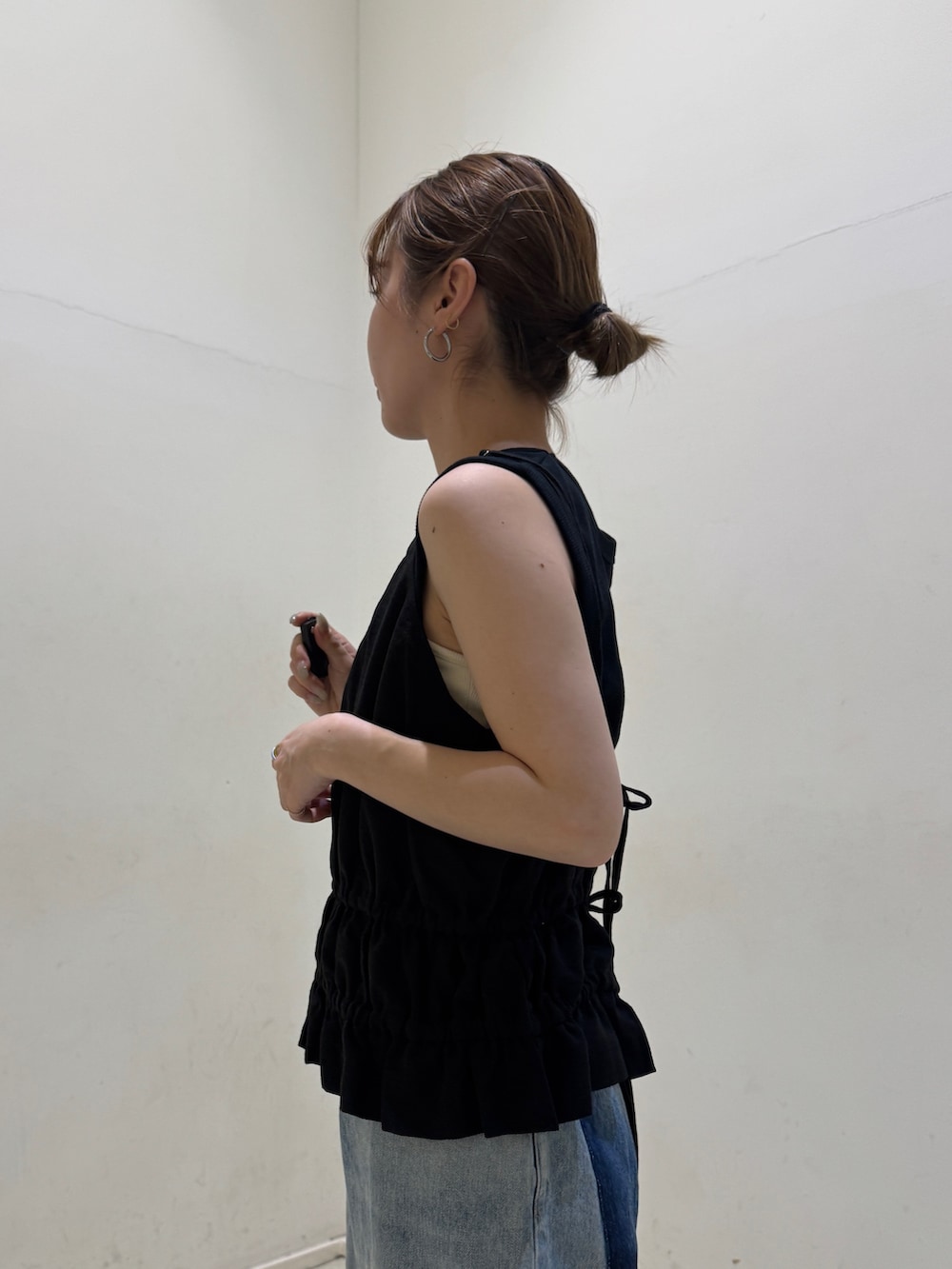 ブラック系のタンクトップ、ブルー系のデニムパンツ、ブラック系のサンダルを着用したレディースの春コーディネートの5枚目の写真