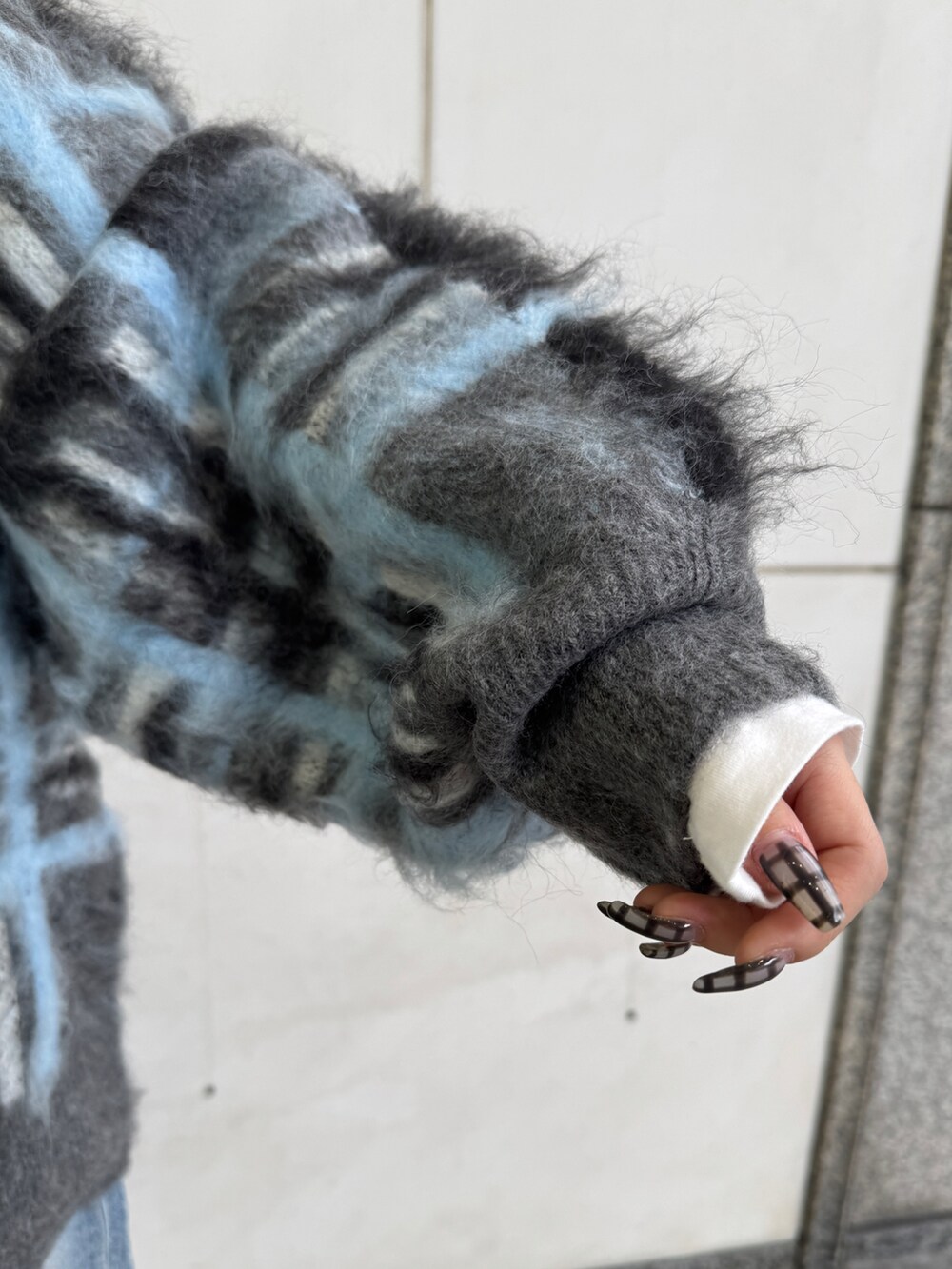 グレー系のニット/セーター、ホワイト系のTシャツ/カットソー、ブルー系のデニムパンツを着用したレディースの秋コーディネートの10枚目の写真