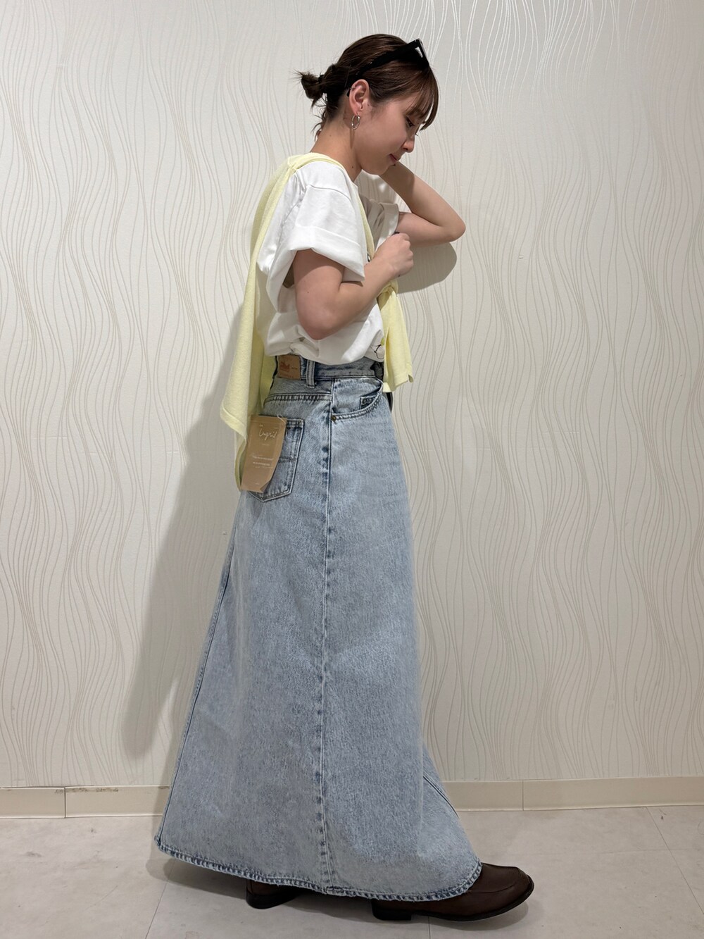 ホワイト系のTシャツ/カットソー、イエロー系のニット/セーター、ブルー系のスカートを着用したレディースの春コーディネートの2枚目の写真