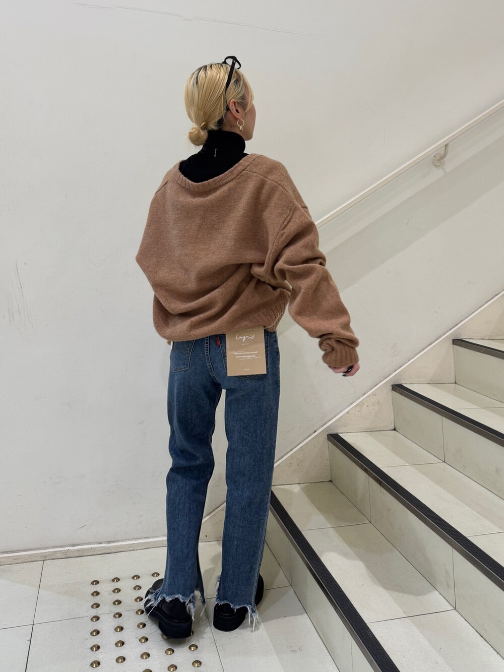 イエロー系のニット/セーター、ブラック系のニット/セーター、ブルー系のデニムパンツを着用したレディースの冬コーディネートの3枚目の写真