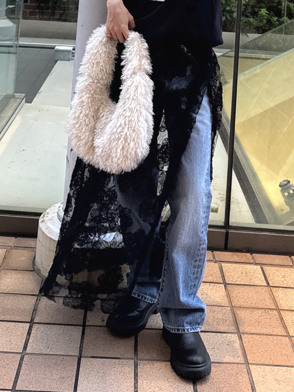 ブラック系のパーカー、ブラック系のスカート、ブルー系のデニムパンツを着用したレディースの秋コーディネートの4枚目の写真