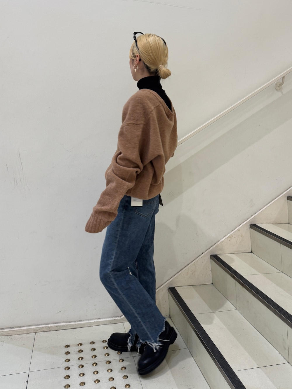 イエロー系のニット/セーター、ブラック系のニット/セーター、ブルー系のデニムパンツを着用したレディースの冬コーディネートの2枚目の写真